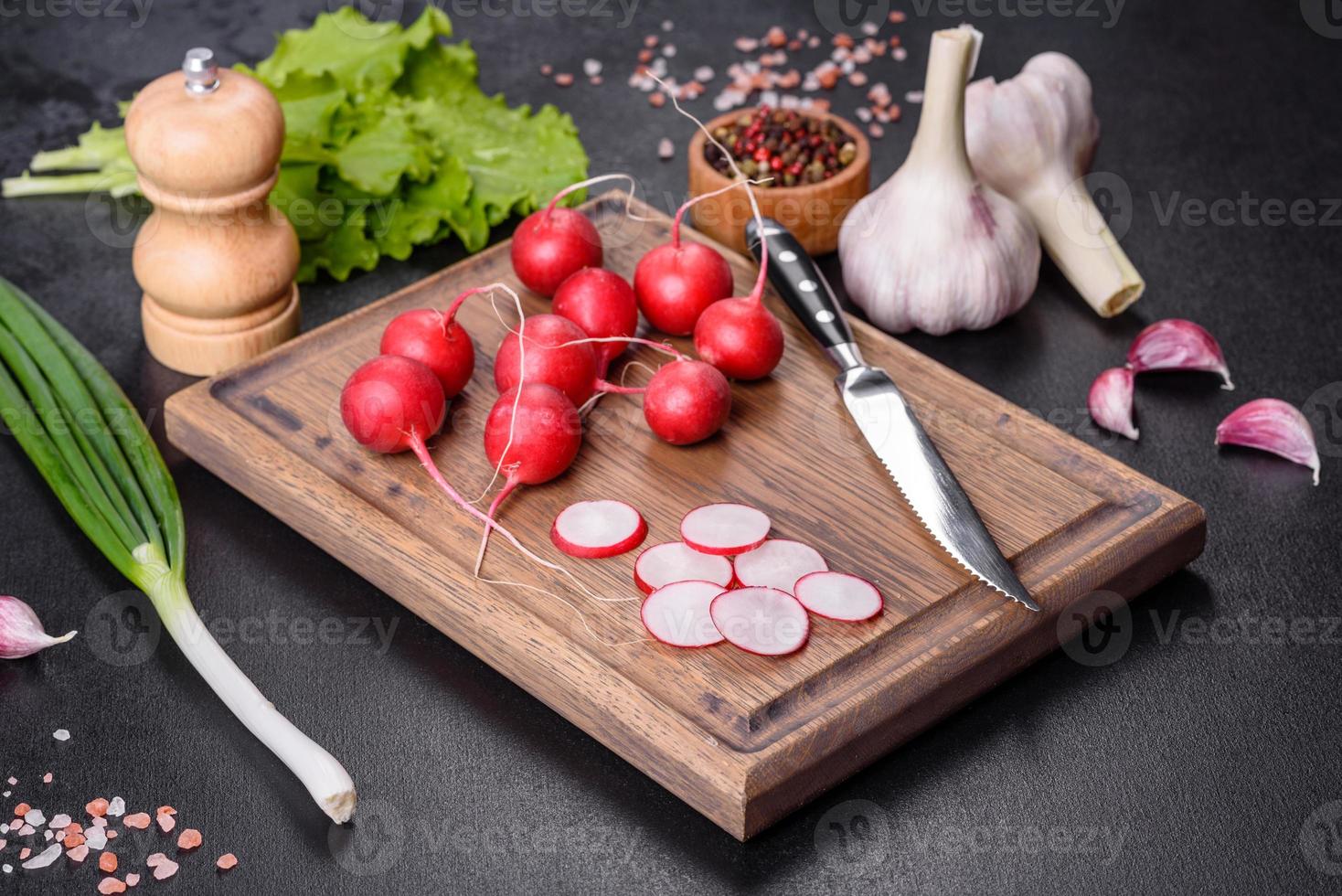 delizioso ravanello rosso fresco come ingrediente per fare l'insalata di primavera sul tagliere di legno foto