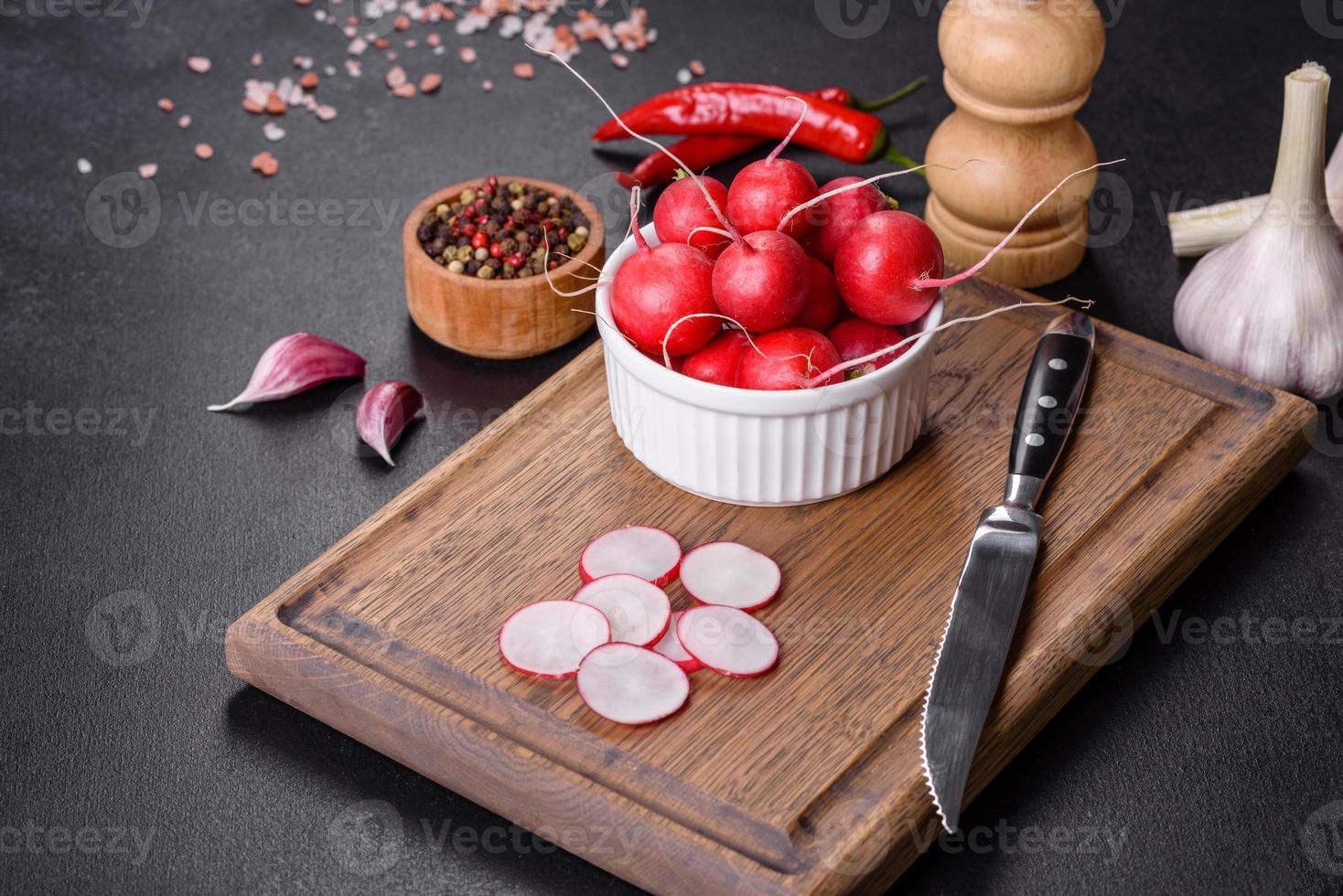 delizioso ravanello rosso fresco come ingrediente per fare l'insalata di primavera sul tagliere di legno foto