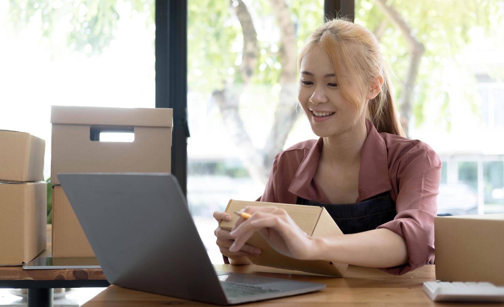 ritratto di giovane donna asiatica sme che lavora con una scatola a casa sul posto di lavoro. proprietario di una piccola impresa di start-up, PMI imprenditore di piccole imprese o business freelance online e concetto di consegna. foto