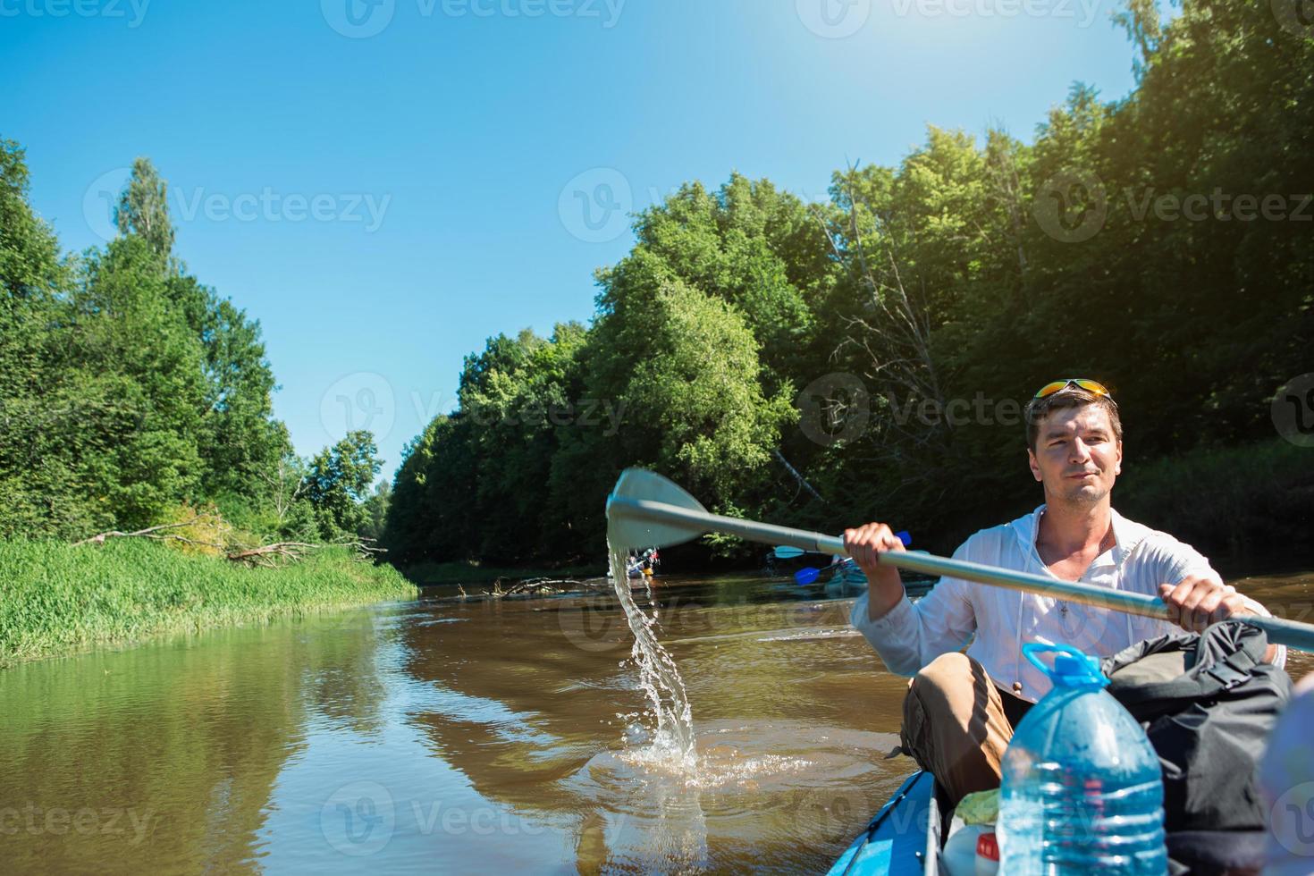 uomo in kayak viaggio in barca a remi sul fiume, un'escursione in acqua, un'avventura estiva. turismo eco-friendly ed estremo, stile di vita attivo e sano foto