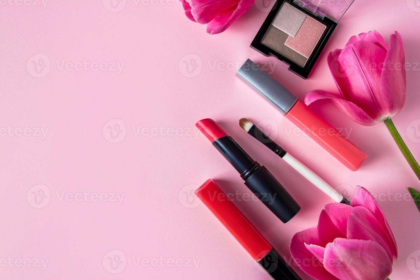 set di cosmetici e fiori su uno sfondo rosa. trucco e prodotti di bellezza. foto