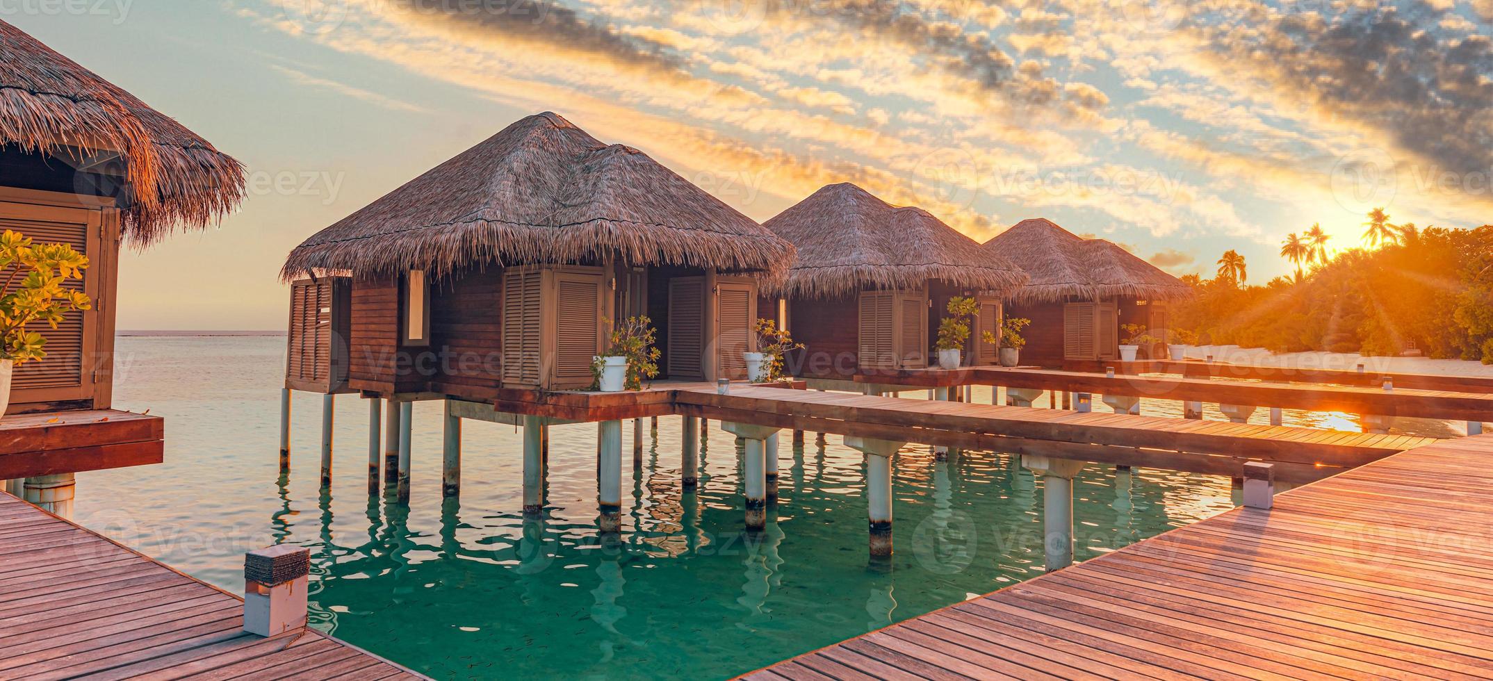 tramonto sull'isola delle maldive, resort di ville sull'acqua di lusso e molo in legno. bel cielo e nuvole e sfondo della spiaggia per le vacanze estive e il concetto di viaggio foto