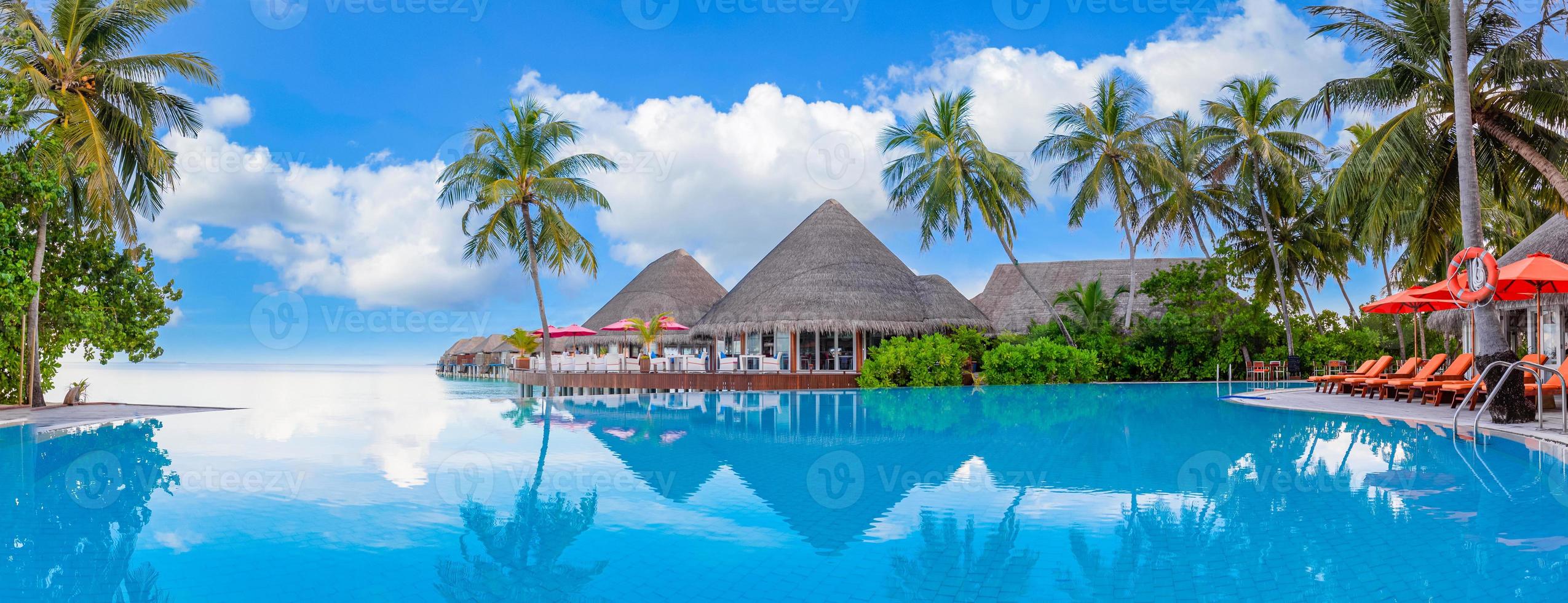 paesaggio del turismo all'aperto. lussuoso resort sulla spiaggia con piscina e sedie a sdraio o lettini ombrelloni con palme e cielo blu, orizzonte marino. l'isola estiva rilassa i viaggi e le vacanze idilliache foto