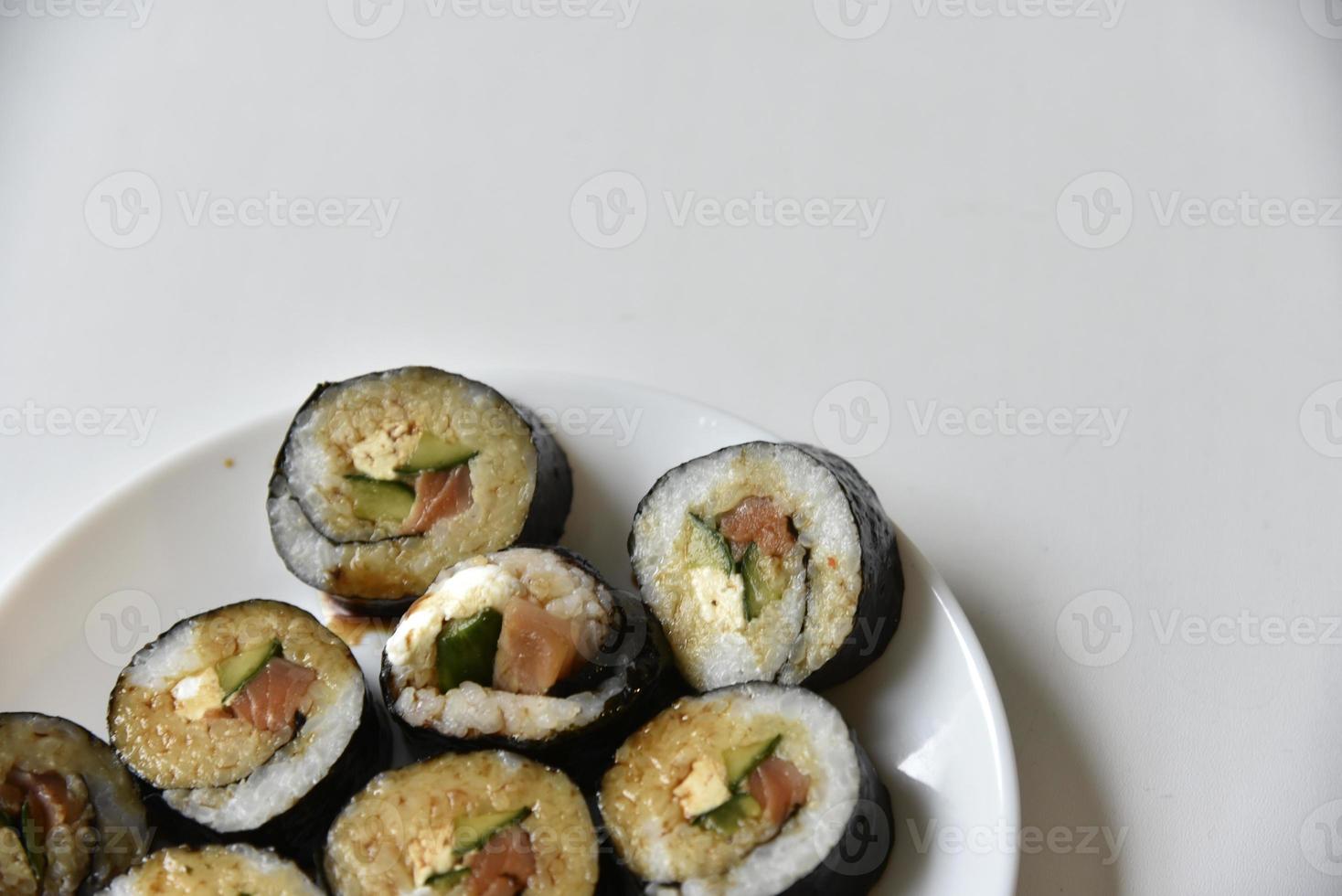 involtini di riso con salmone e formaggio su un piatto bianco. sushi giapponese. foto