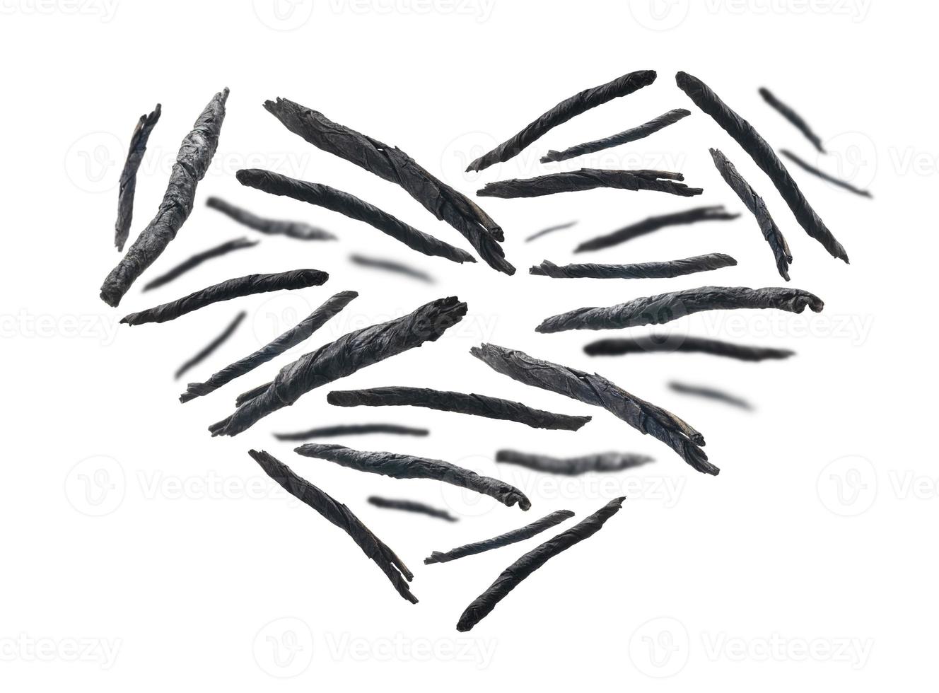 foglie contorte secche di tè kuding a forma di cuore su sfondo bianco foto