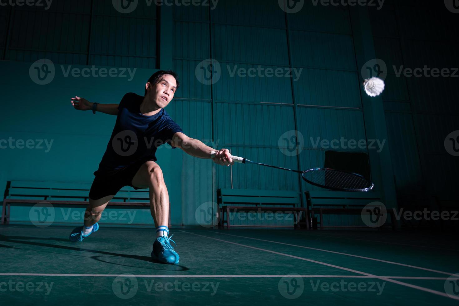 il giocatore professionista di badminton usa la racchetta colpendo il volano o il volano sul campo durante il riscaldamento prima della competizione del torneo nel tipo a uomo singolo nel campo al coperto foto