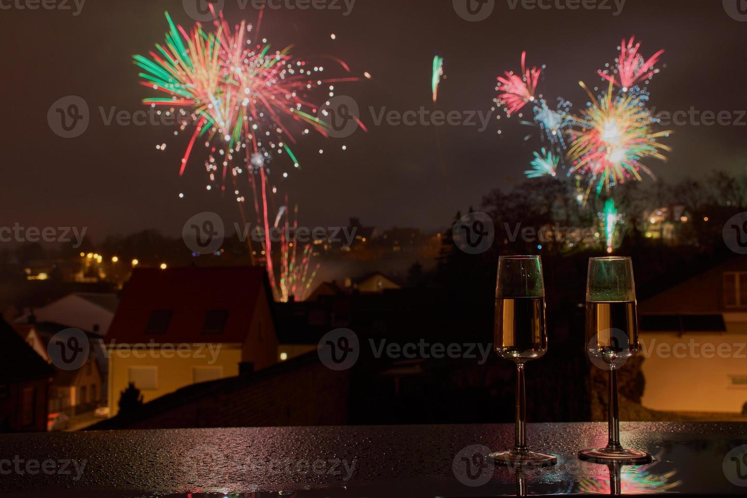 fuochi d'artificio di capodanno dietro due bicchieri di spumante foto