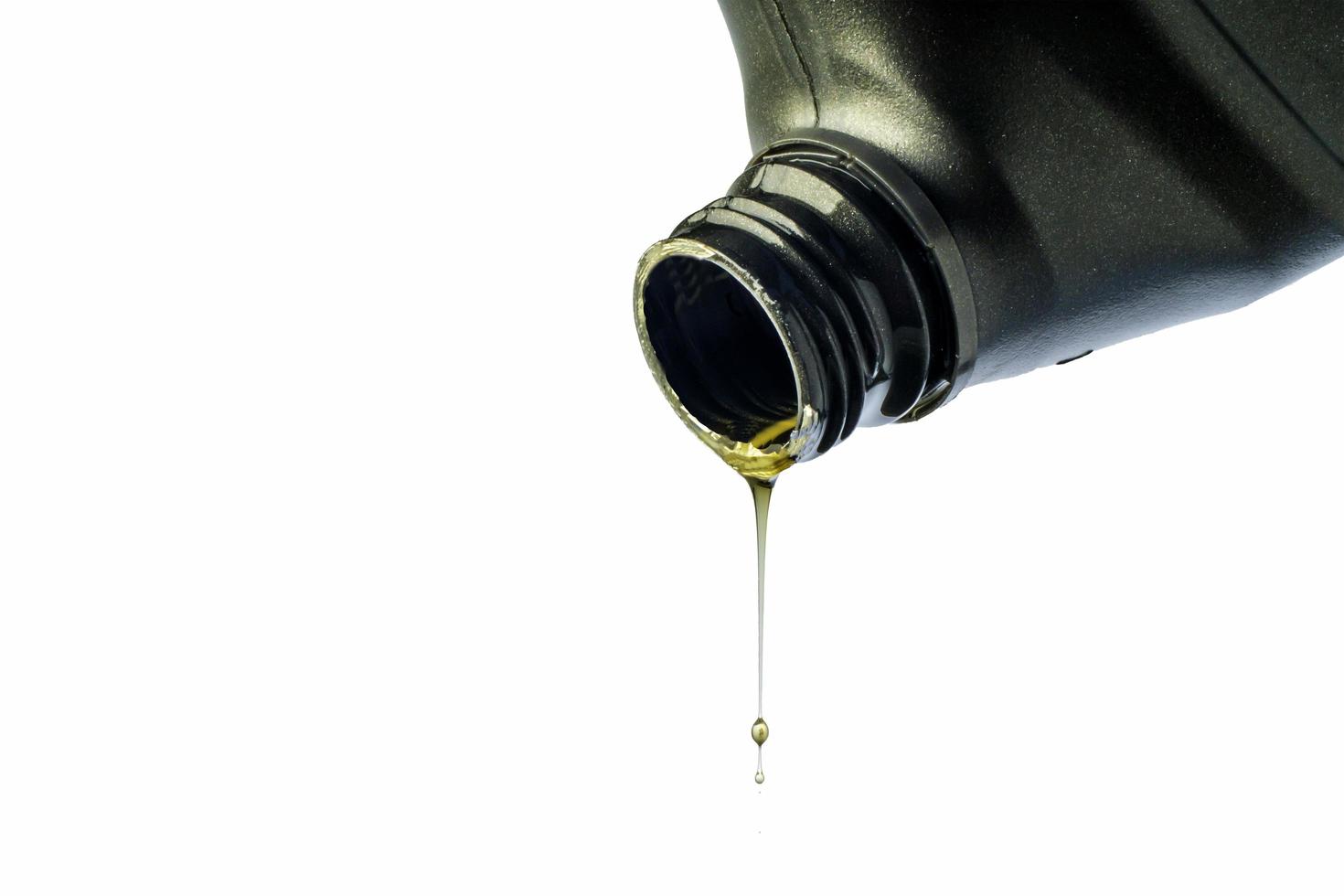 il lubrificante per auto scorre dalla bottiglia grigia su sfondo bianco isolato. foto