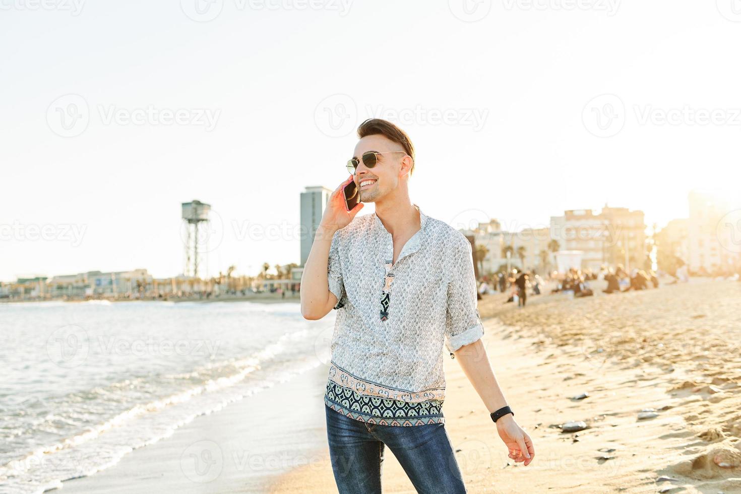 un uomo che parla al telefono sulla spiaggia foto