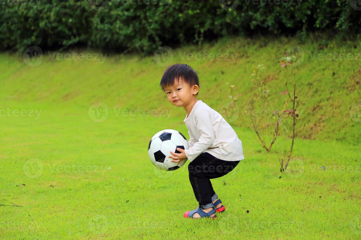 ragazzo asiatico tenere la palla in mano. bambino che gioca a calcio al parco. foto