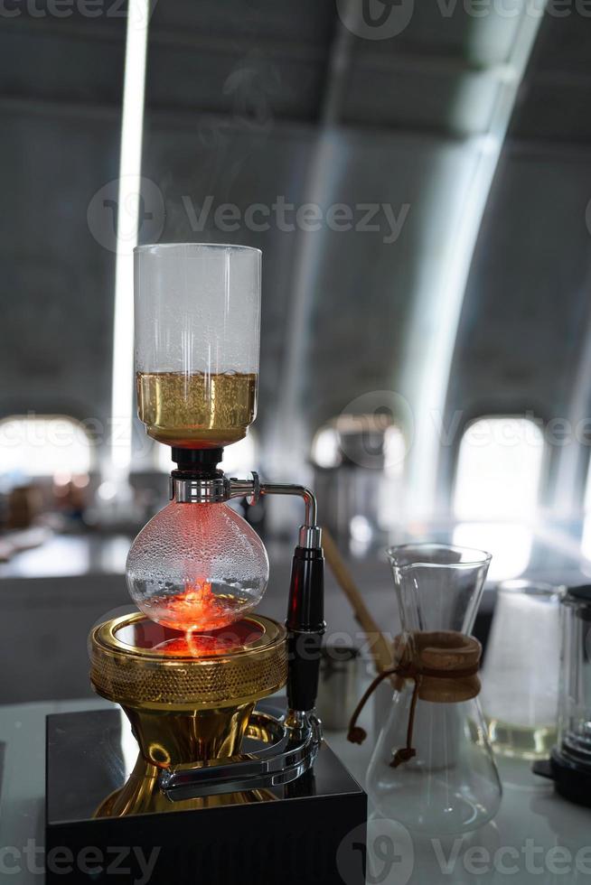 sifone o caffettiera a sifone che prepara caffè espresso caldo sul tavolo da bar nella caffetteria foto