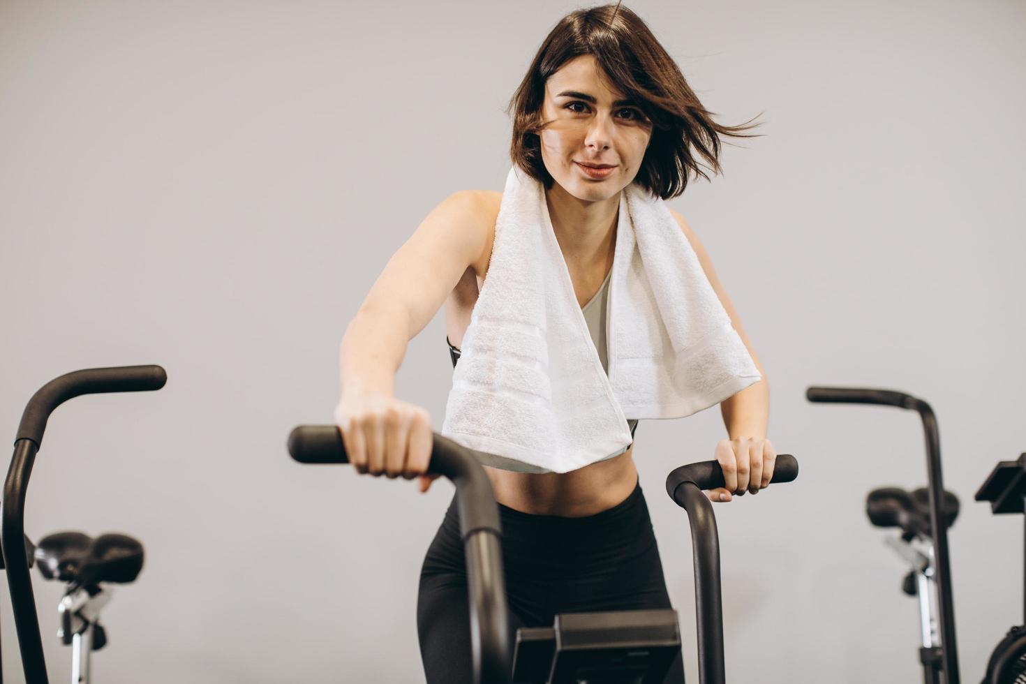 donna crossfit che fa un intenso allenamento cardio su cyclette foto