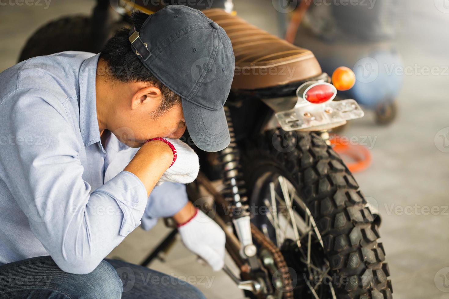 concetti di riparazione e manutenzione, uomo che ripara moto in officina, meccanico che ripara moto in officina foto