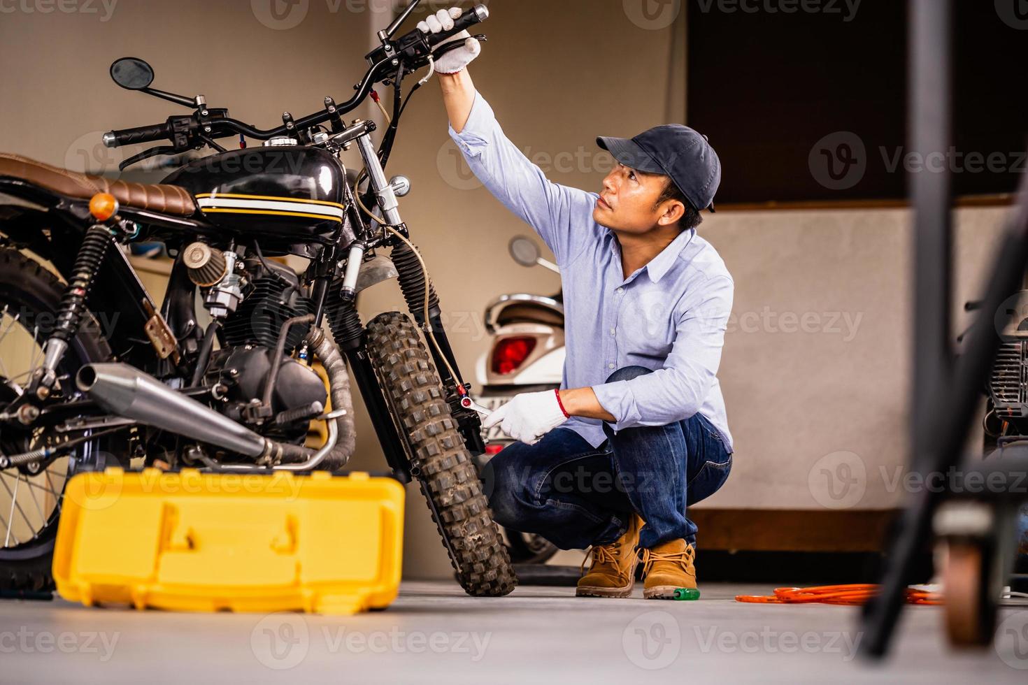 concetti di riparazione e manutenzione, uomo che ripara la motocicletta in officina, riparazione meccanica e controllo della moto del sistema frenante nel garage dell'officina foto