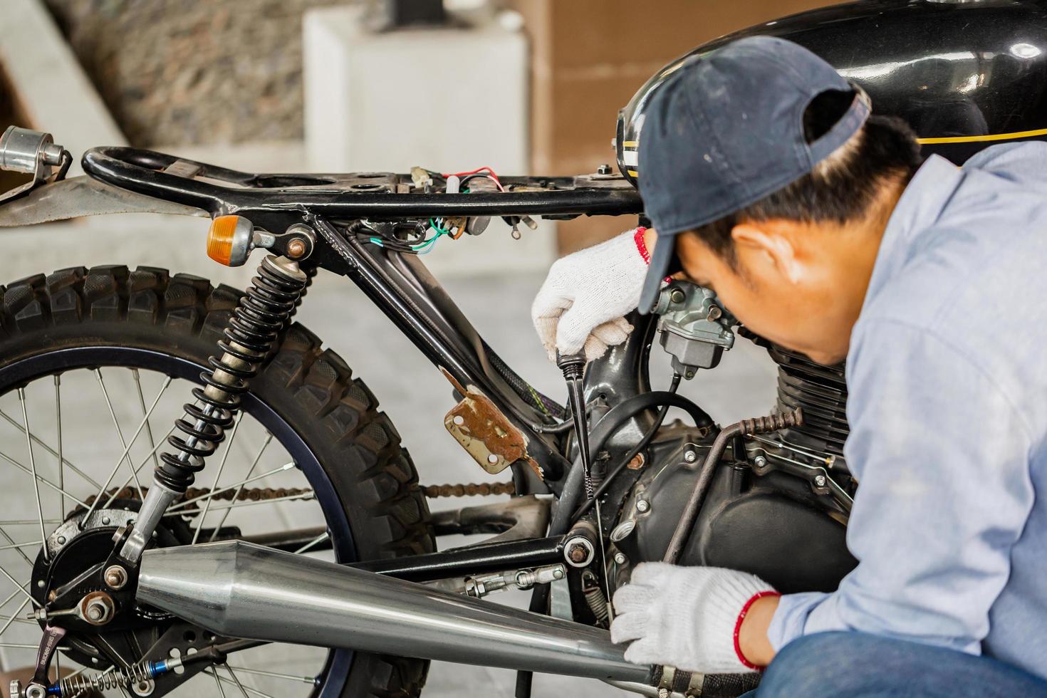 concetti di riparazione e manutenzione, uomo che ripara moto in officina, meccanico che ripara moto in officina foto