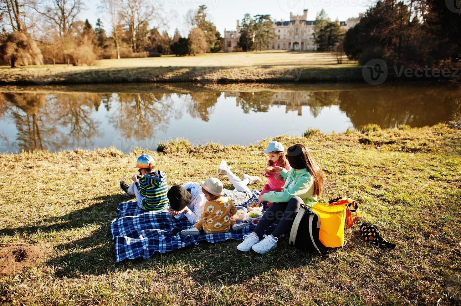 madre con quattro bambini che fanno picnic vicino a pound al parco di lednice contro il castello, repubblica ceca. foto
