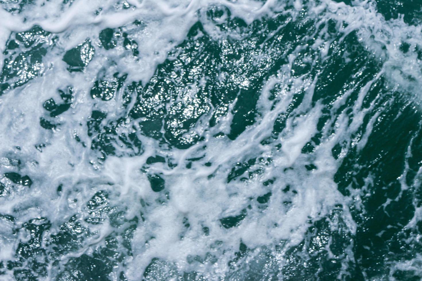 bellissime onde del mare con schiuma di colore blu e turchese. acqua di mare blu astratta con onda bianca. onde bianche e blu della strada della nave sull'oceano di mare dell'acqua. foto