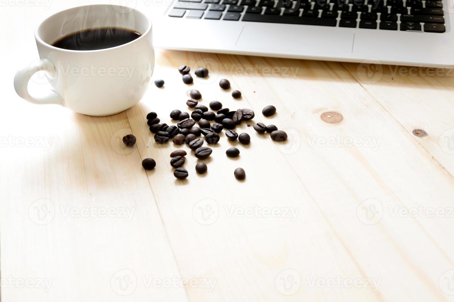 una tazza di caffè, laptop e chicchi di caffè spalmabili foto