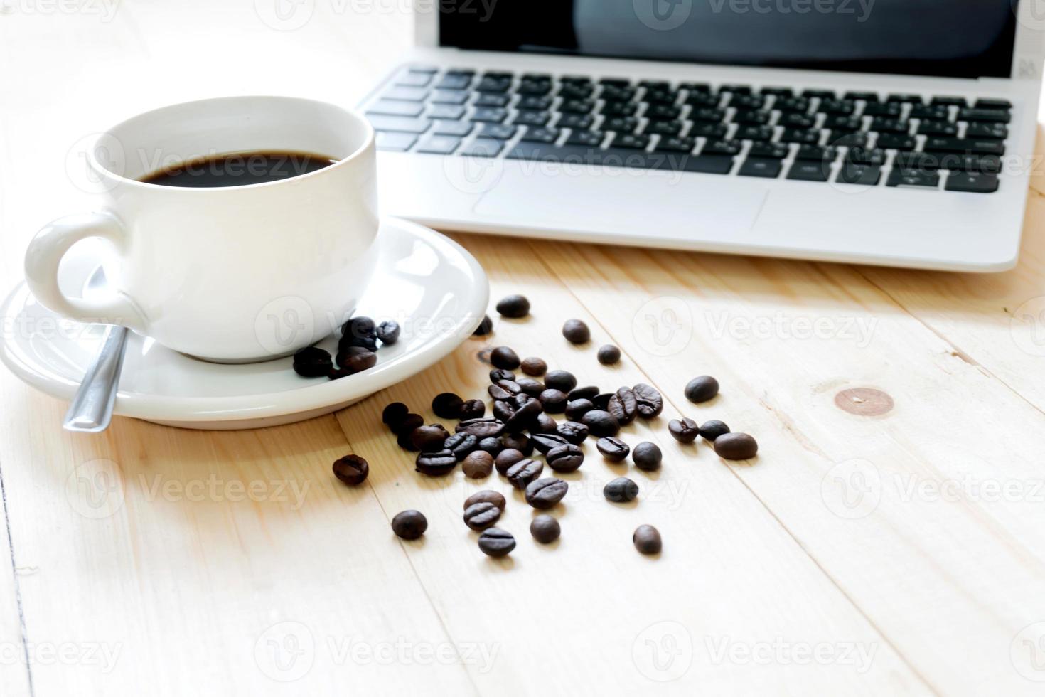 una tazza di caffè, laptop e chicchi di caffè spalmabili foto