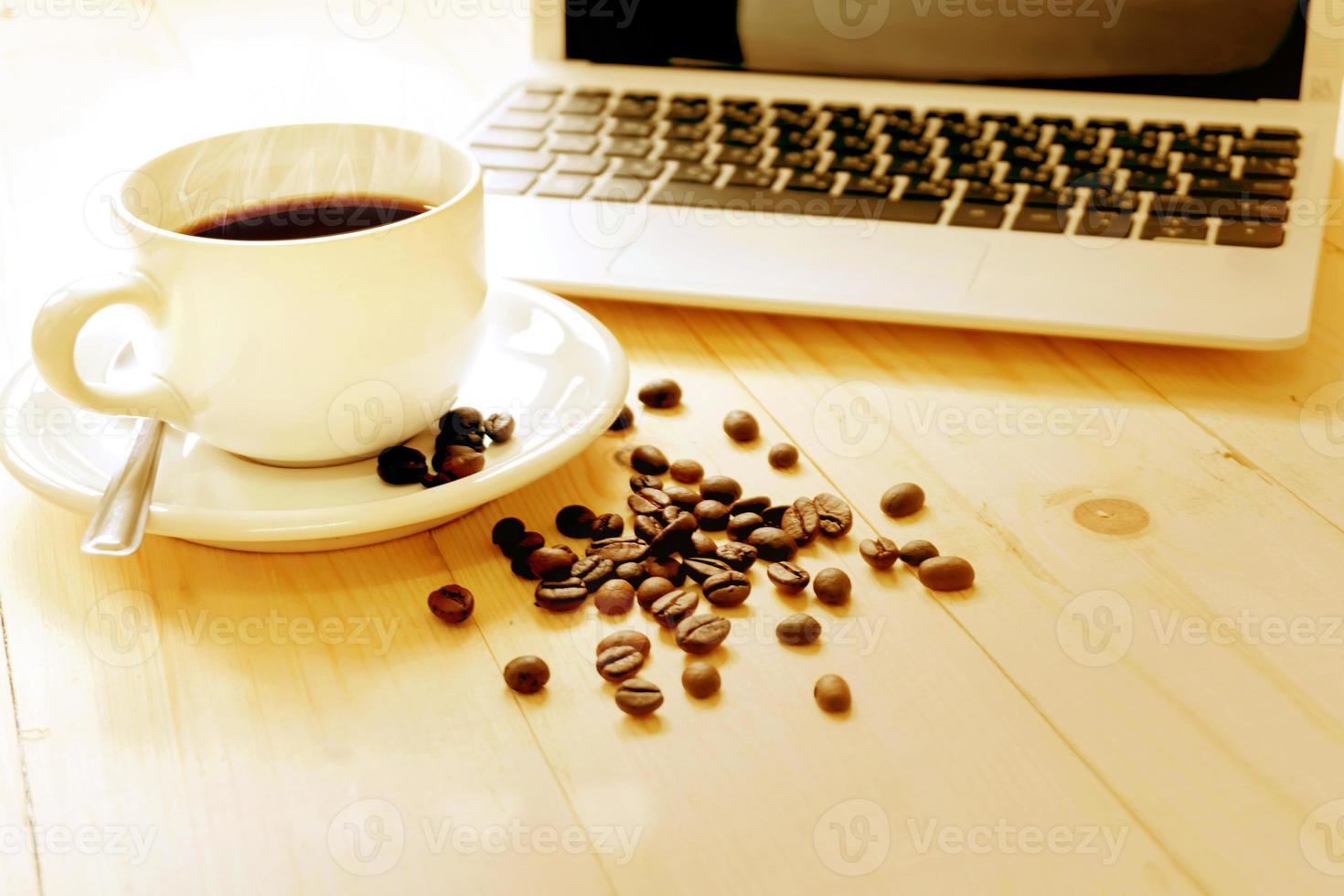 una tazza di caffè, laptop e chicchi di caffè spalmabili foto