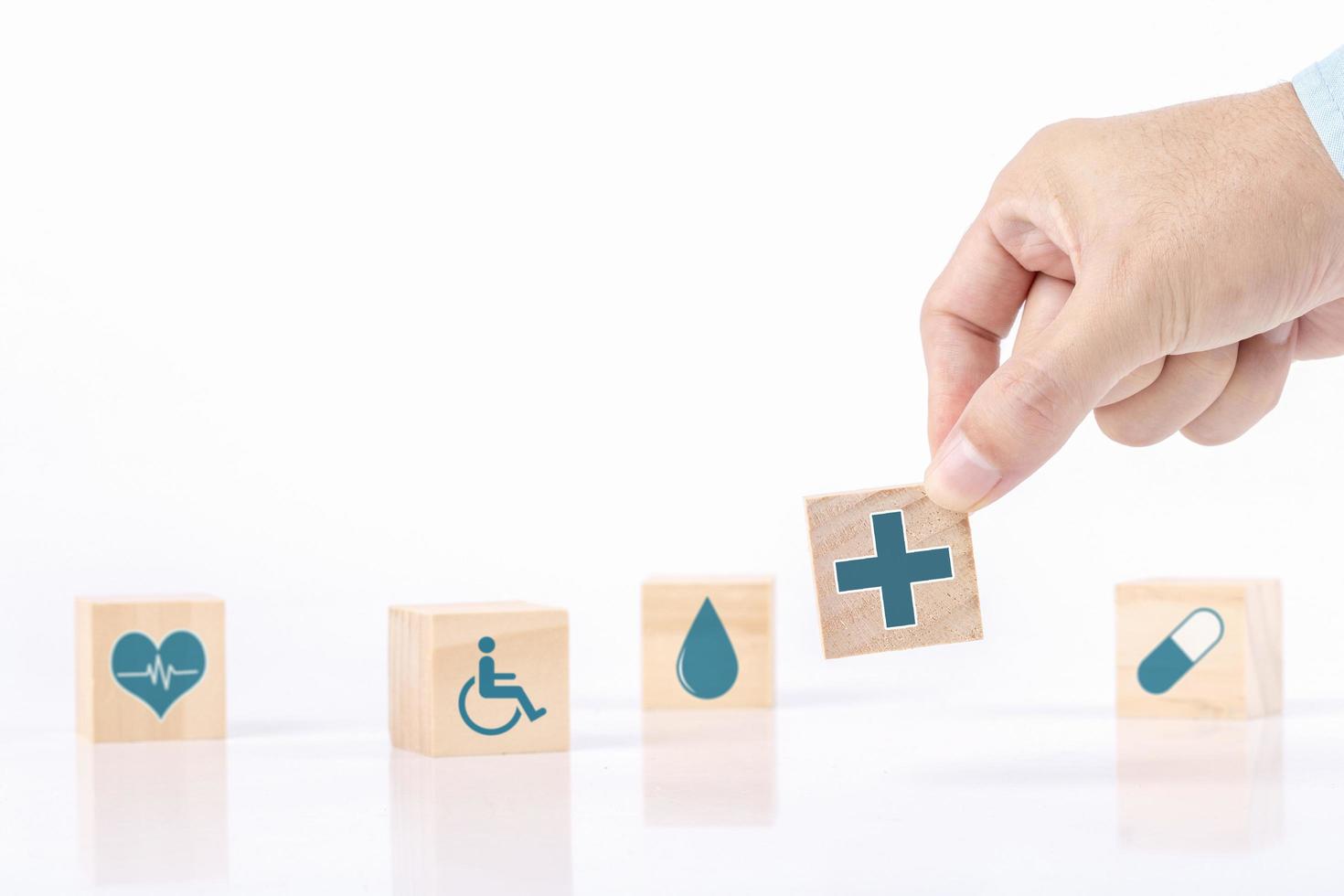 la mano sceglie un simbolo medico sanitario delle icone di emoticon sul blocco di legno, sul concetto di assicurazione sanitaria e medica foto