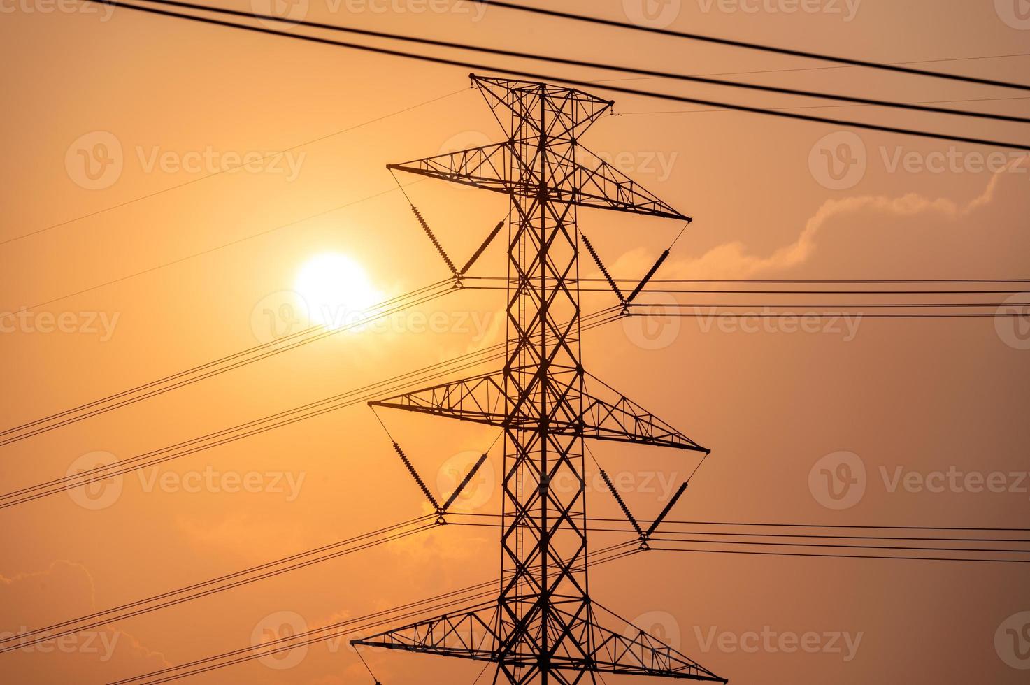 palo dell'alta tensione, torre di trasmissione con il sole sul campo in campagna al tramonto foto