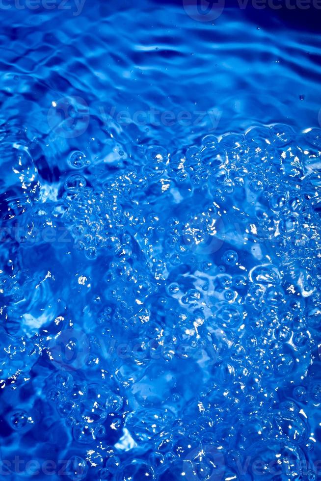 sfondo blu scuro dell'acqua con schizzi e bolle. foto