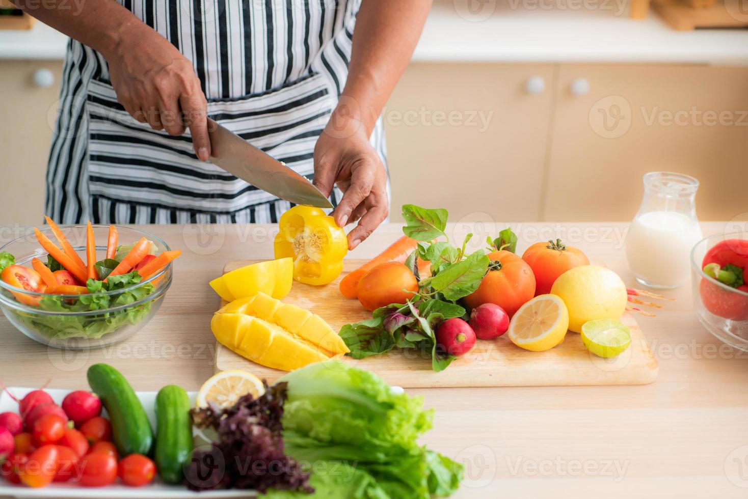 verdure e frutta come mango, limoni, peperoni, pomodori, carote vengono preparate sulla tavola e su un tagliere da tagliare, per le insalate in cucina. foto