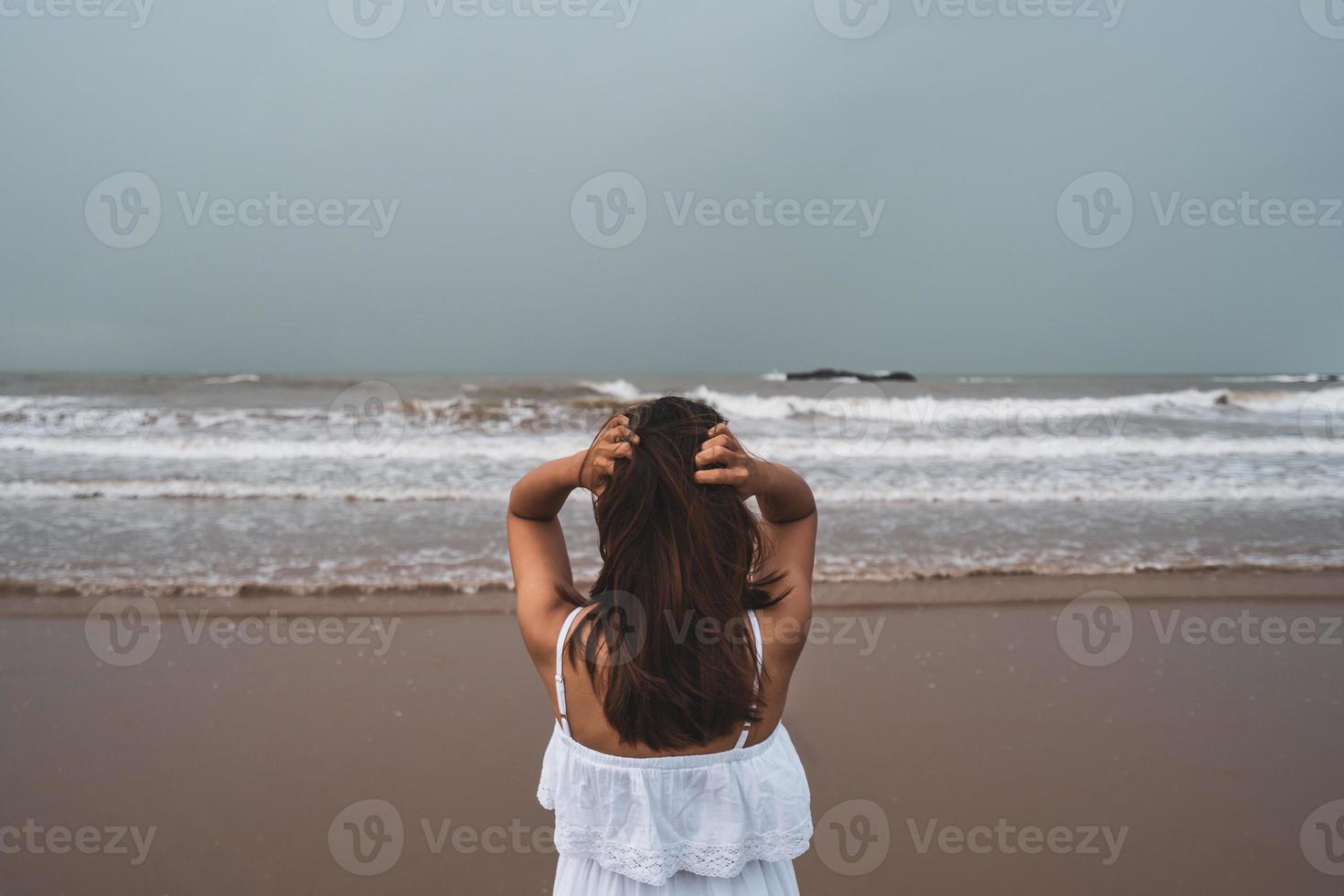 giovane donna che si sente sola e triste guardando il mare in una giornata uggiosa foto