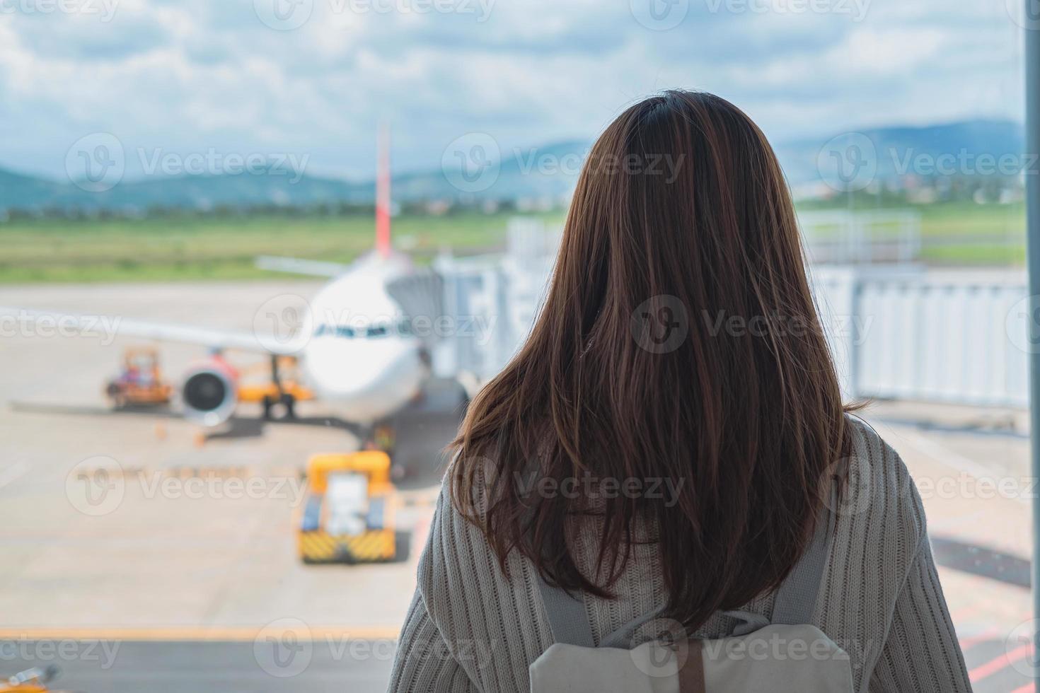 viaggiatore della giovane donna che esamina l'aereo all'aeroporto, concetto di viaggio foto