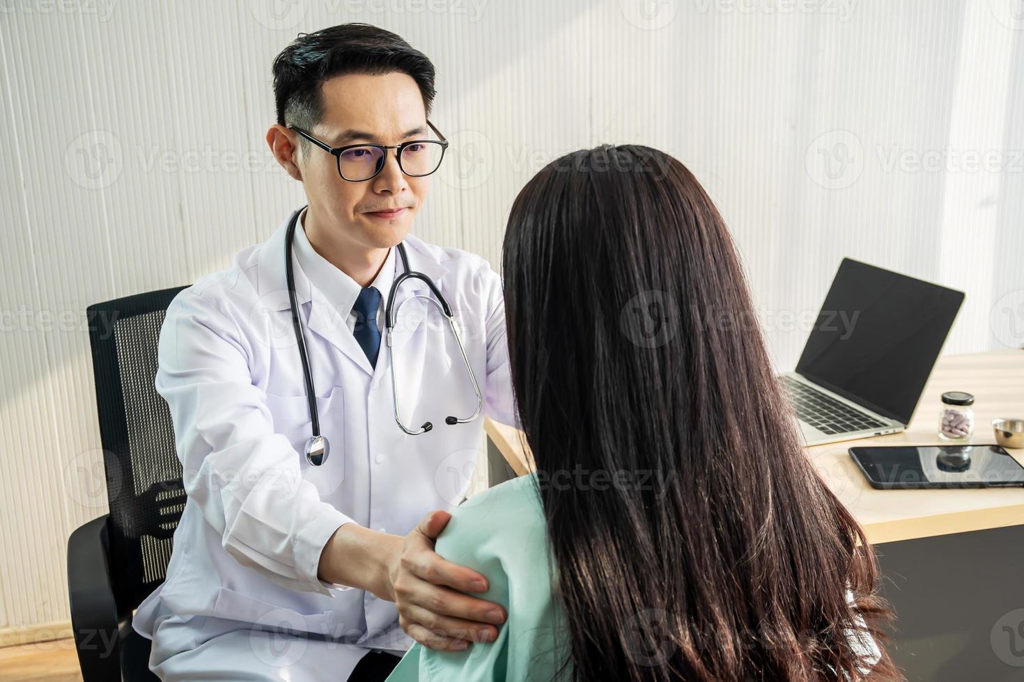 medico maschio amichevole che consola la paziente femminile e usa la mano sulla spalla per aiutarla a rilassarsi in ufficio durante il ricevimento, il concetto di consulenza e assistenza sanitaria. foto