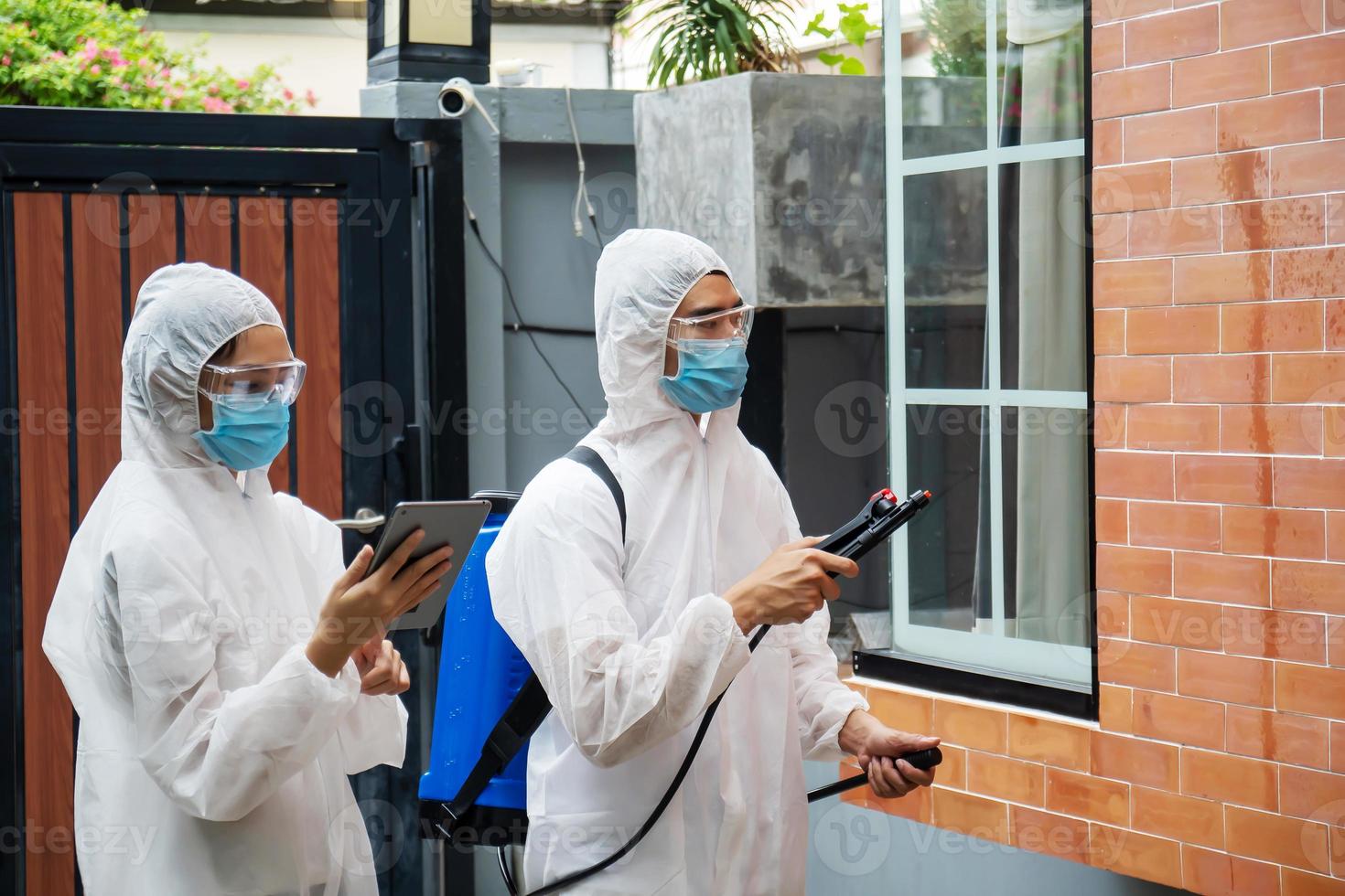 l'uomo e le donne indossano tute protettive personali, occhiali e maschere che effettuano la disinfezione e la decontaminazione in un luogo pubblico o in una casa per ridurre la diffusione della malattia durante la crisi covid-19. foto