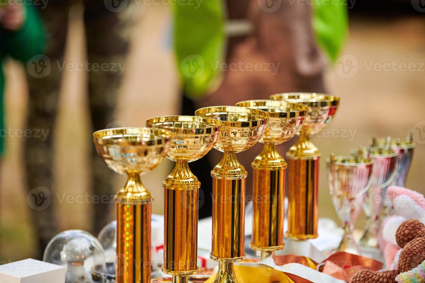 trofei d'oro dei campioni, molte coppe d'oro lucide allineate in fila sul tavolo, premi dei trofei foto