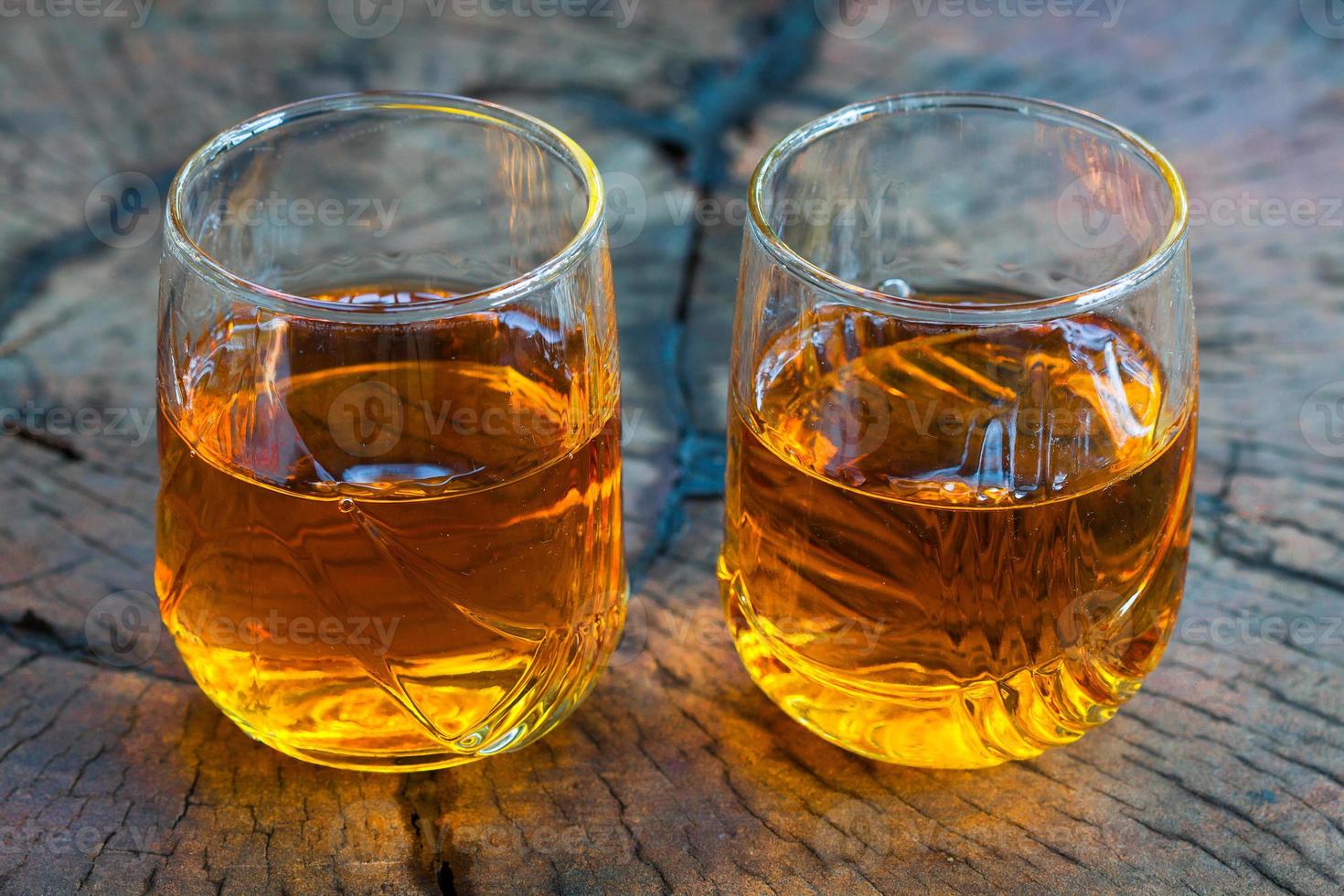 whisky marrone dorato sulle rocce in un bicchiere foto