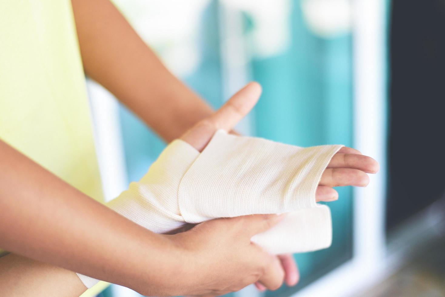 braccio di bendaggio della ferita della mano da parte dell'infermiera - concetto di pronto soccorso e medicina per lesioni al polso foto
