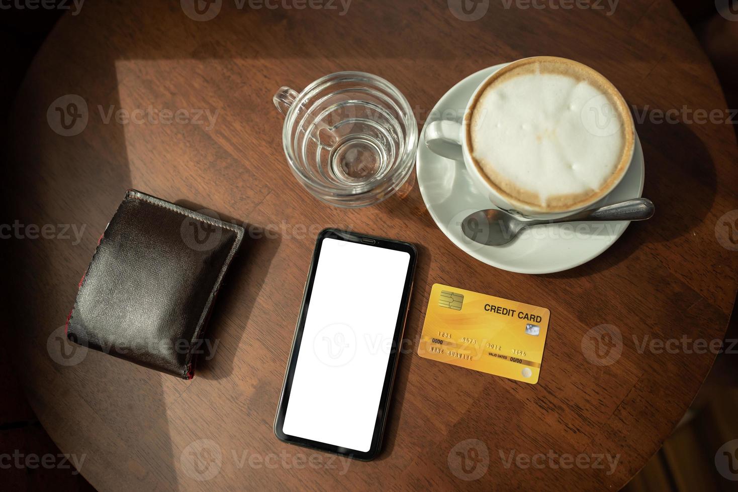 carte di credito e telefono sono posizionati su un tavolo di legno presso la caffetteria. foto