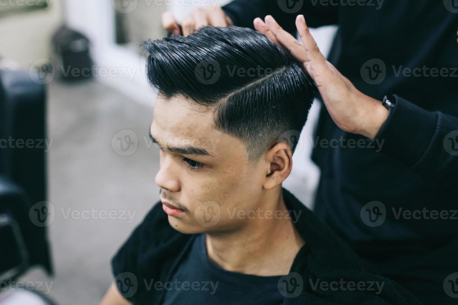 giovane dal barbiere. radersi i capelli con l'aiuto di un parrucchiere. cura di sé, bellezza maschile. barbiere. acconciatura moderna foto