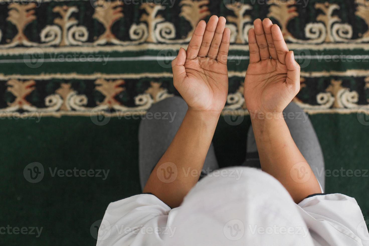 vista dall'alto la mano di un uomo musulmano che prega allah nella moschea foto