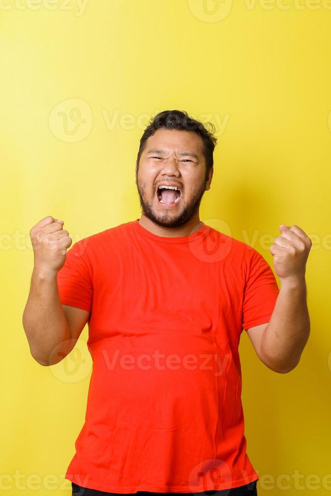 attraente giovane uomo asiatico grasso alzando i pugni con la bocca che urla la faccia, sì gesto, celebrando il successo, foto