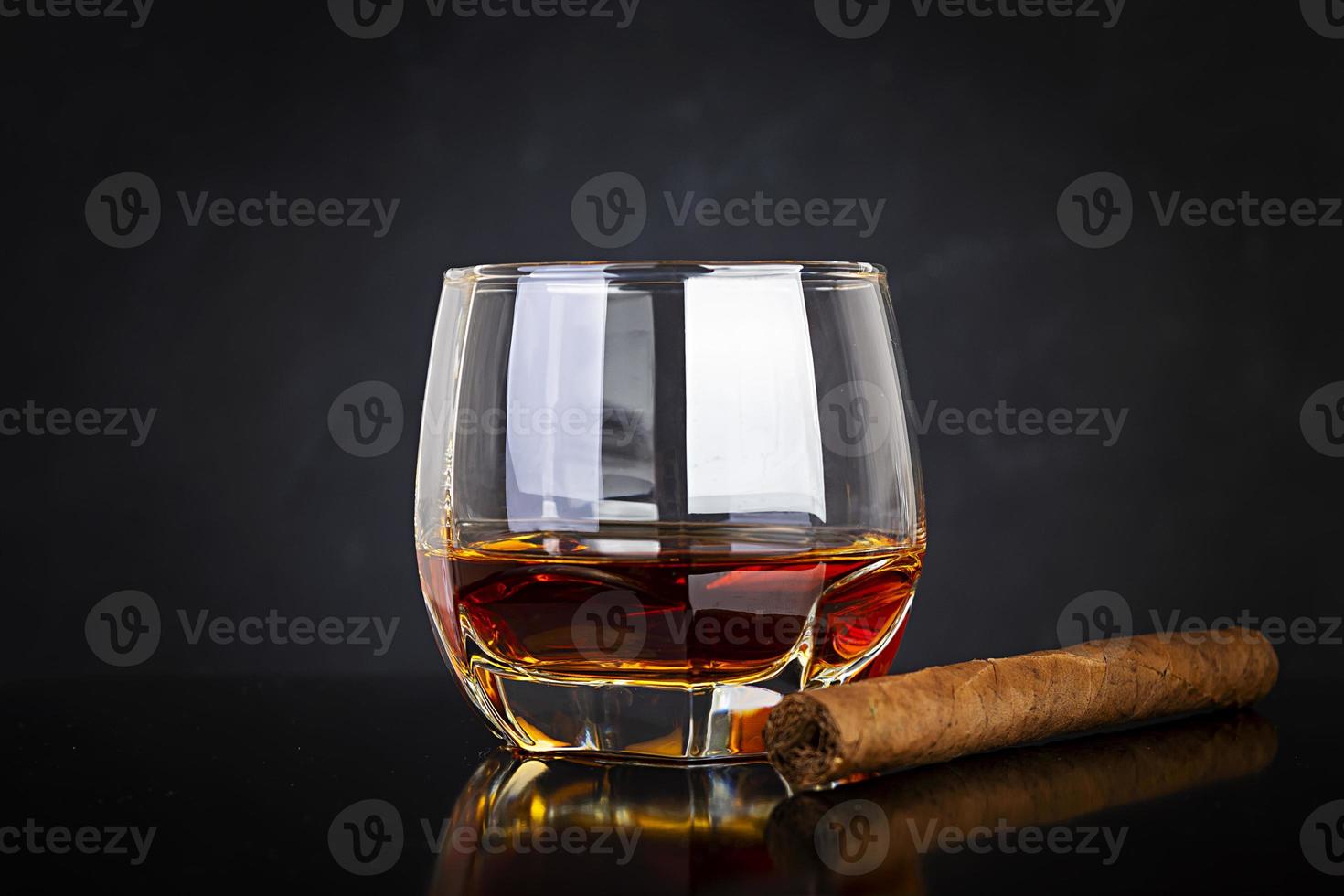 bicchiere di whisky e sigaro su sfondo scuro. foto