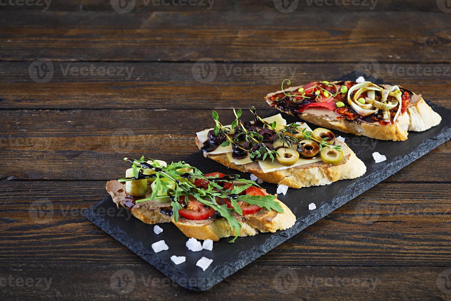 bruschetta con pasta di fegatini di pollo. deliziose bruschette con vari ripieni. diverse bruschette ob fondo in legno foto