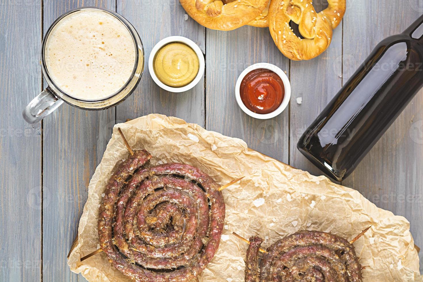 menu del cibo per l'oktoberfest. salsiccia con salsa diversa, pretzel e bicchiere di birra scura foto