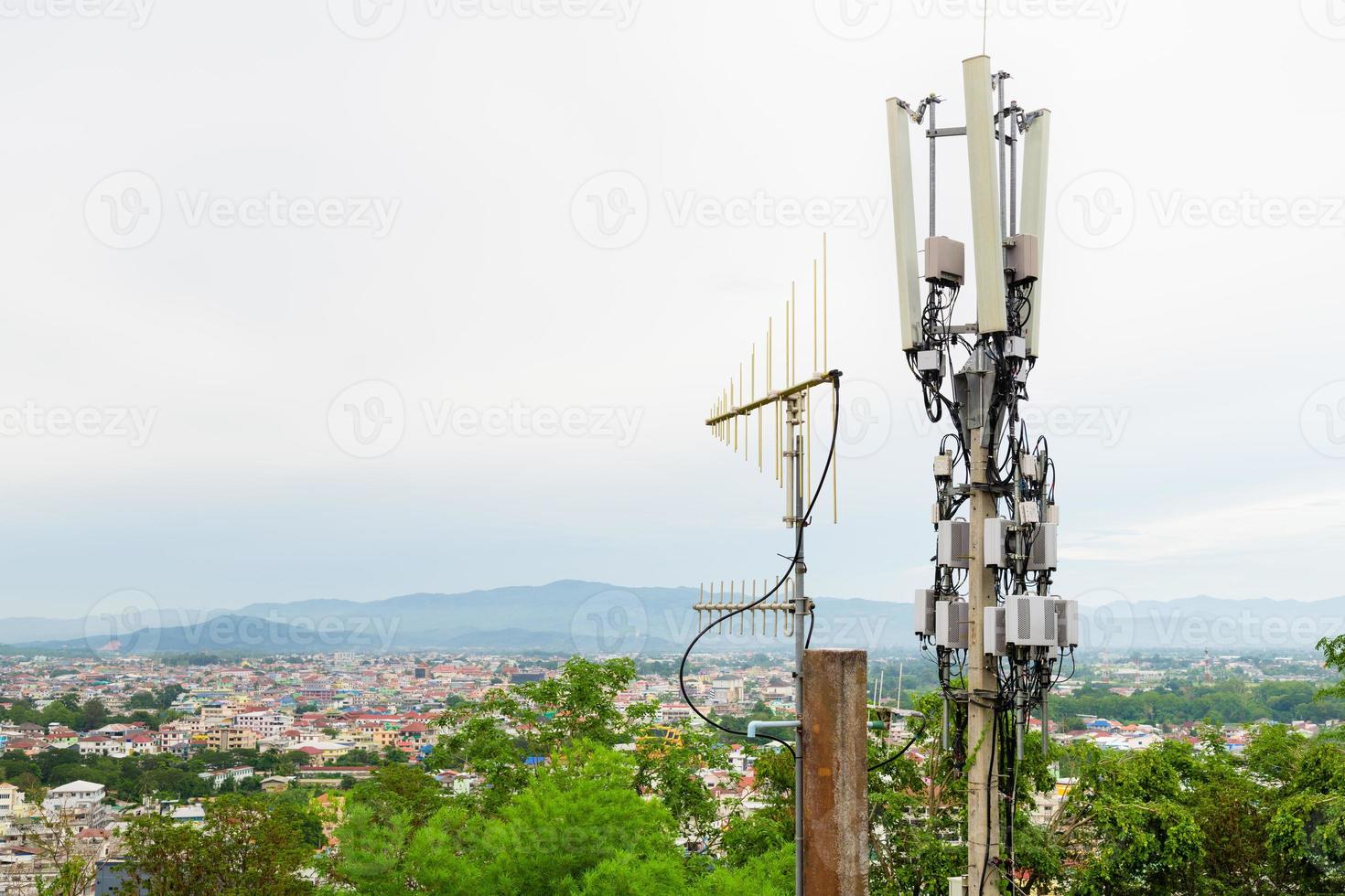 torre di telecomunicazioni con antenna di rete cellulare 5g su una città sullo sfondo della valle foto