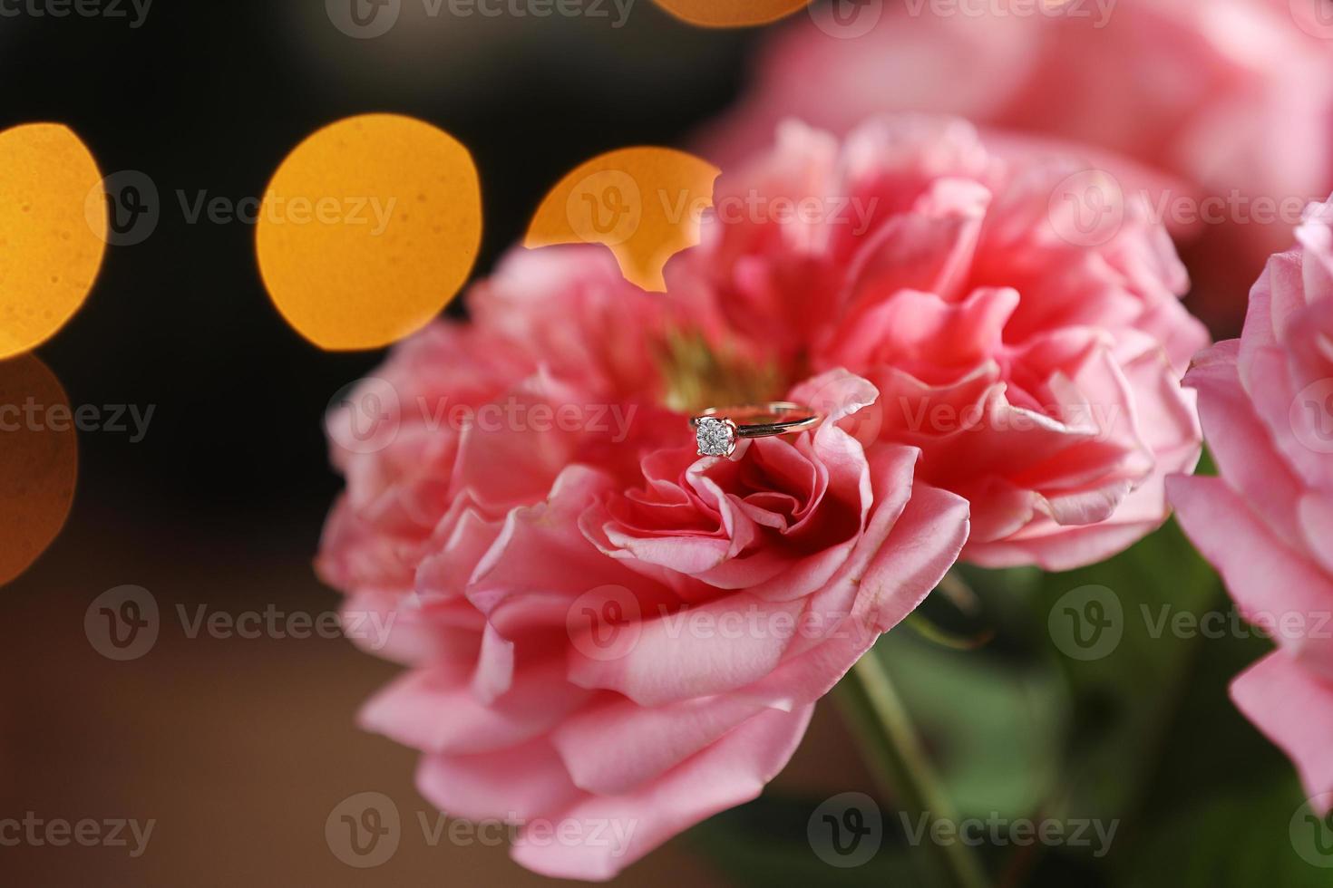 anello in oro con diamante. fedi nuziali di diamanti su petali di rosa. anello di diamanti su rosa rosa. messa a fuoco selettiva foto