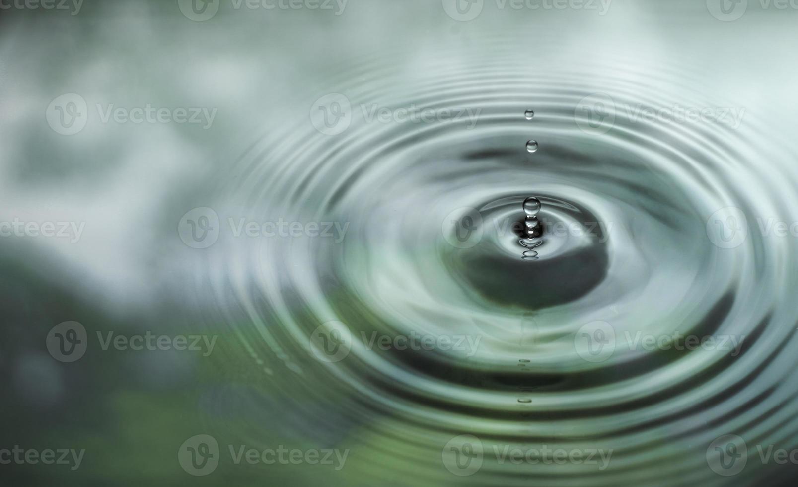 l'acqua gocciola sulla superficie dell'acqua nella foresta pluviale. con il riflesso delle foglie verdi foto