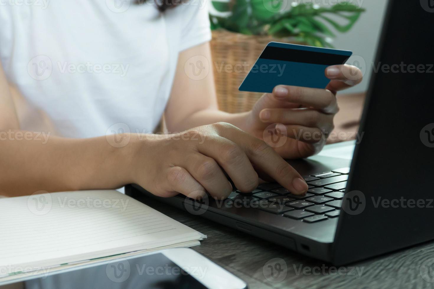 mani che tengono la carta di credito e utilizzano il laptop. acquisti online. concetto di lavoro da casa foto