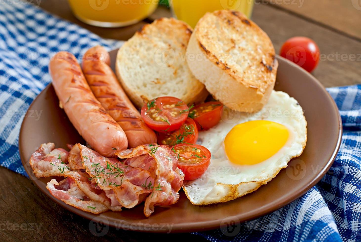 colazione all'inglese - pane tostato, uova, pancetta e verdure in stile rustico su fondo di legno foto