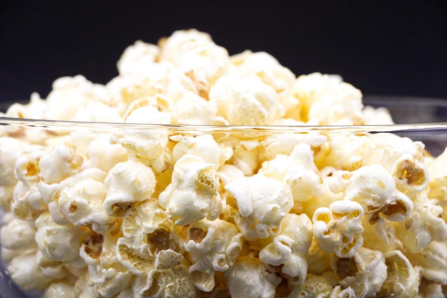 popcorn in una tazza di vetro posta su sfondo nero. foto