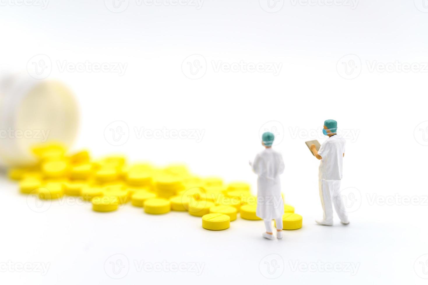 concetto medico e sanitario. primo piano due medici in miniatura con file di pazienti in piedi con pillole gialle con bottiglia su sfondo bianco. foto