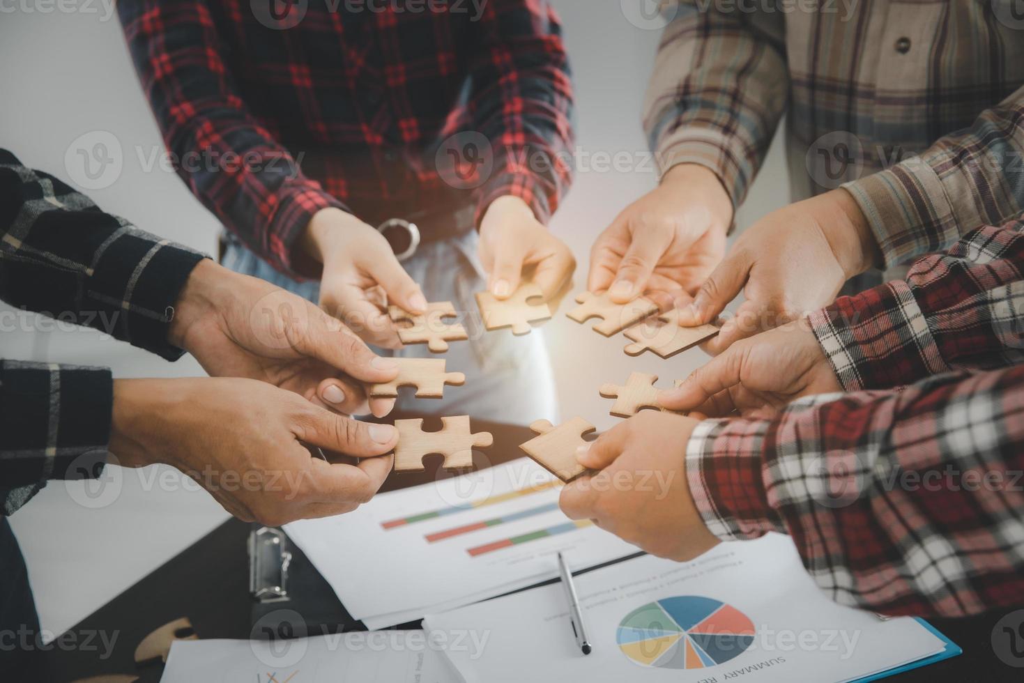 mani di persone diverse che assemblano puzzle, il team mette insieme i pezzi alla ricerca della giusta corrispondenza, aiuta il supporto nel lavoro di squadra per trovare un concetto di soluzione comune, vista ravvicinata dall'alto foto